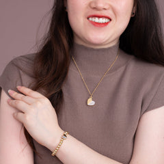 Woman wearing gold locket necklace meaningful jewelry everyday layering
