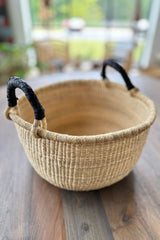 Made Brave Bolga basket used as a plant basket on a wood floor